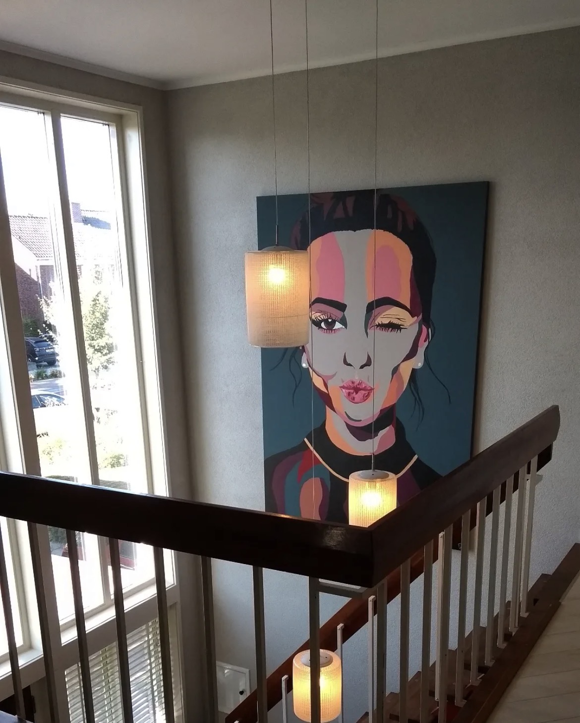 Commissioned blue portrait of a woman blowing a kiss, hanging in a stairwell