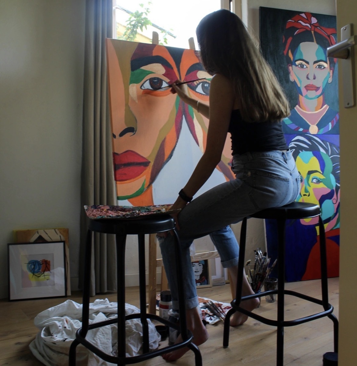 Fabienne painting a large colourful portrait in her sunlit studio