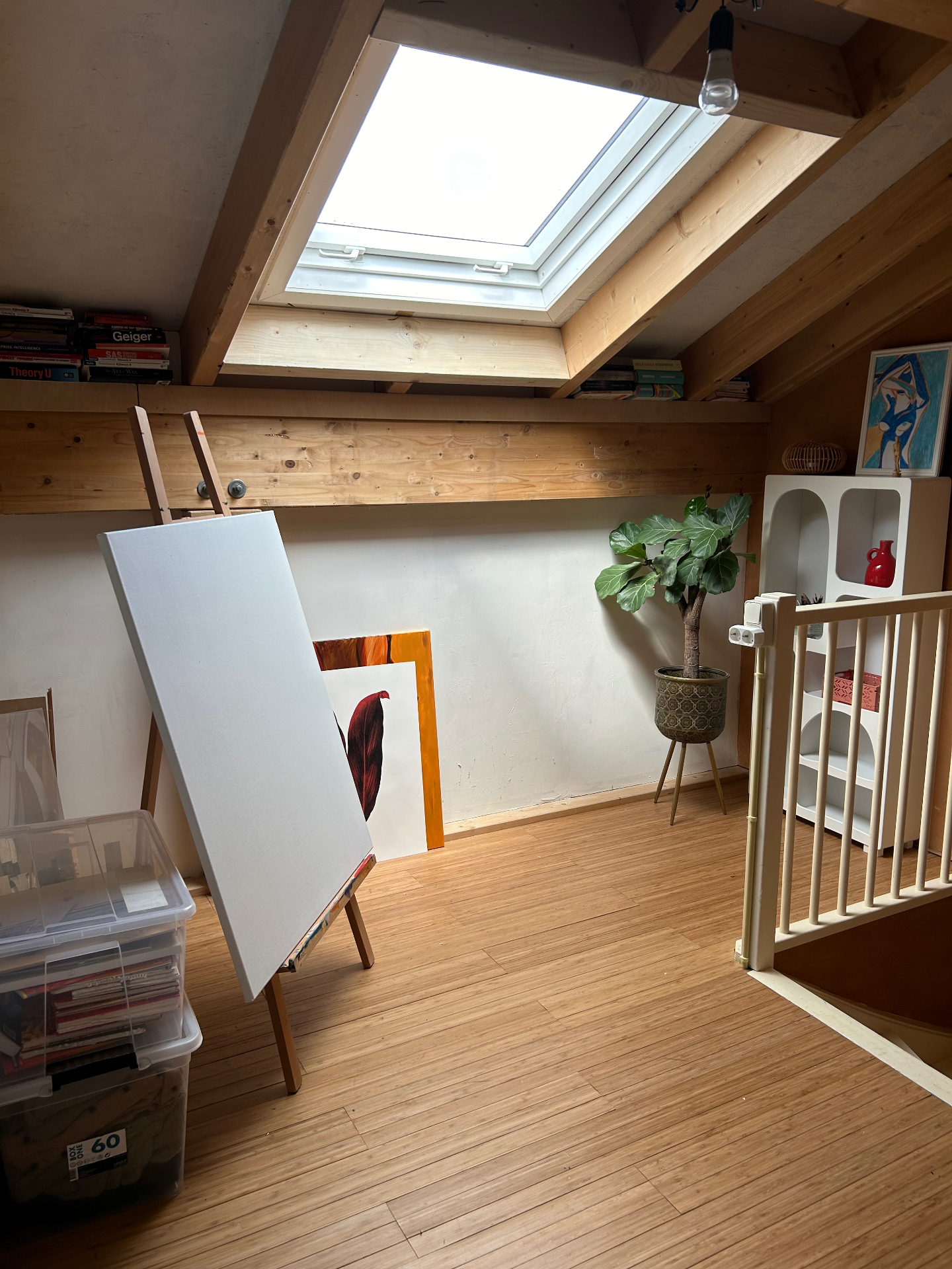 Sunlit artist studio with wooden beams, an easel and canvases waiting to be painted