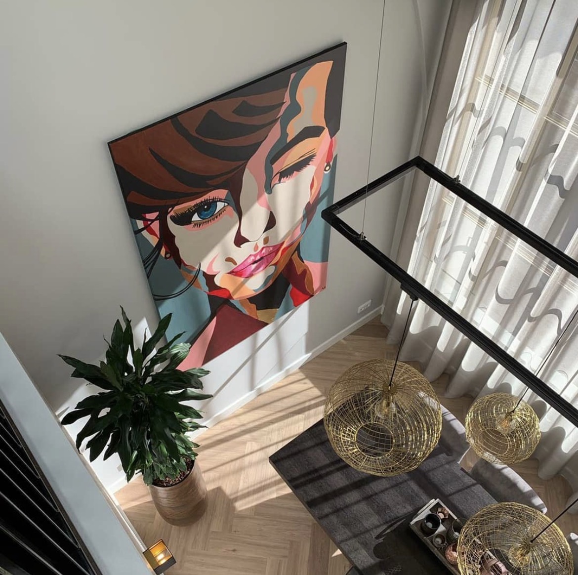 A finished colourful portrait painting hanging on a light wall in a bright modern interior